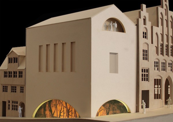 Das Architekturmodell zeigt eine moderne Erweiterung eines historischen Gebäudes. Auffällig sind die gewölbten, beleuchteten Öffnungen und kleine Figuren, die die geplante Nutzung veranschaulichen.