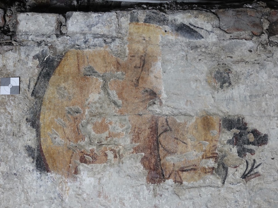 Wandmalerien in Kolk 16-18 Die Wandmalerei zeigt verblasste, historische Motive mit erkennbaren Gesichts- und Pflanzenfragmenten. Der Erhaltungszustand ist stark beeinträchtigt, doch Farbspuren und Konturen lassen eine kunsthistorische Bedeutung vermuten.