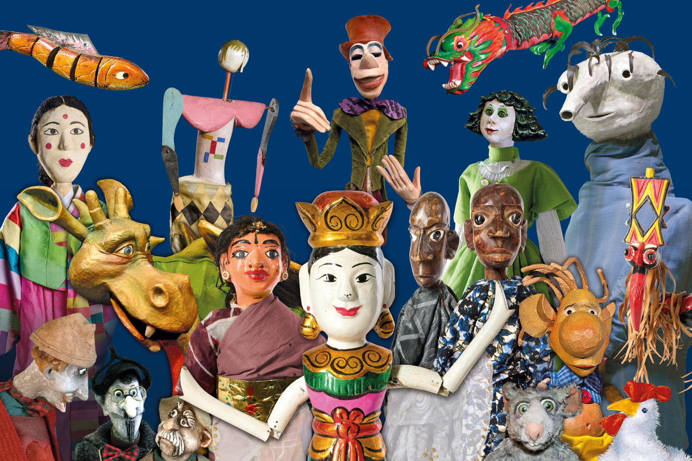 Ein farbenfrohes Ensemble aus verschiedenen Figuren, darunter Marionetten, Stabpuppen und Handpuppen, die aus unterschiedlichen Kulturen und Stilrichtungen stammen. Die Figuren sind kunstvoll gestaltet und detailreich inszeniert, vor einem tiefblauen Hintergrund.